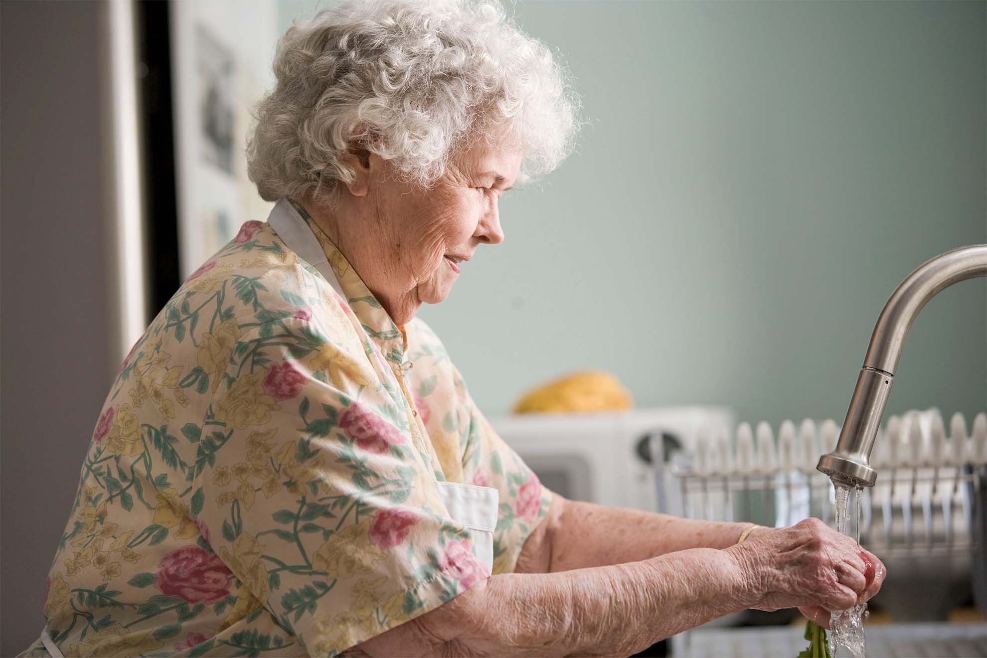 old woman washing things in sink